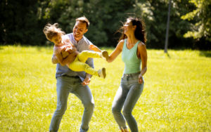 Happy young family with young daughter playing in the park on a sunny day