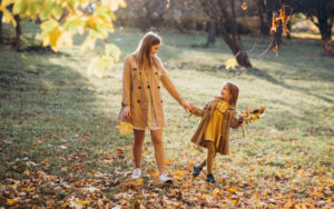 Mother and her daughter have fun and walk in the autumn park
