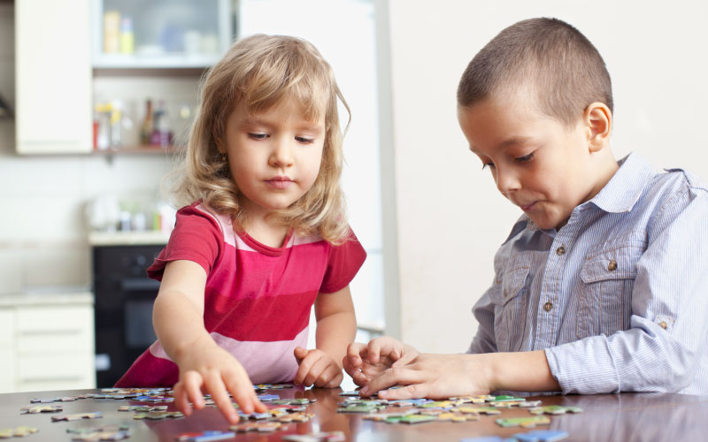 Two younger school-aged children doing a puzzle together