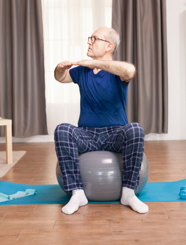 An older man doing exercises on a therapy ball