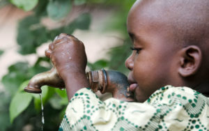 child turning on water spigot for a drink