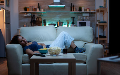 Woman up late at night watching tv on the sofa